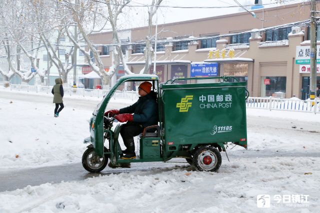 顶风冒雪邮政ems快递员行驶在路上